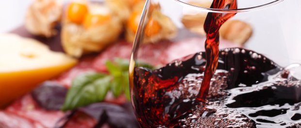 Pouring wine into glass and food background